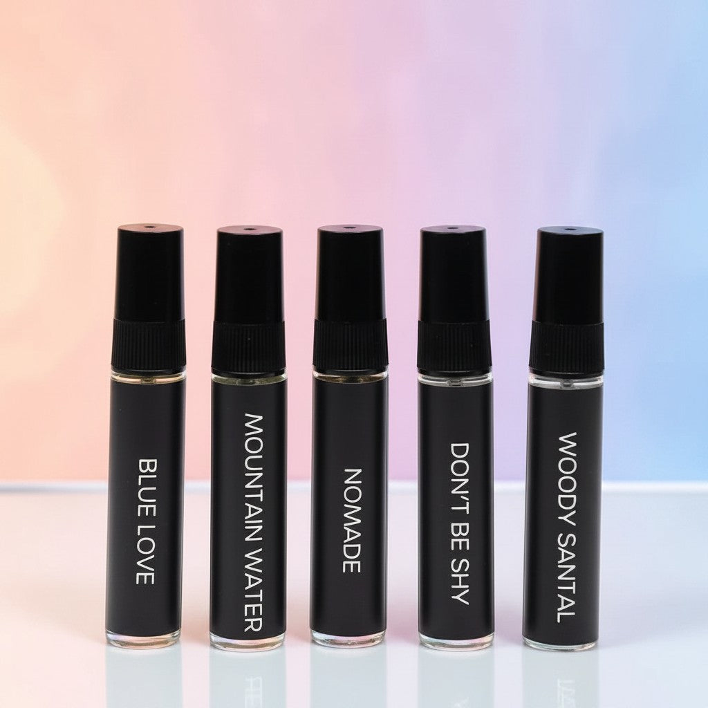 Ambrosia Scents Fragrance Testers Collection: 5 black spray bottles with labels: Blue Love, Mountain Water, Nomade, Don't Be Shy, Woody Santal.