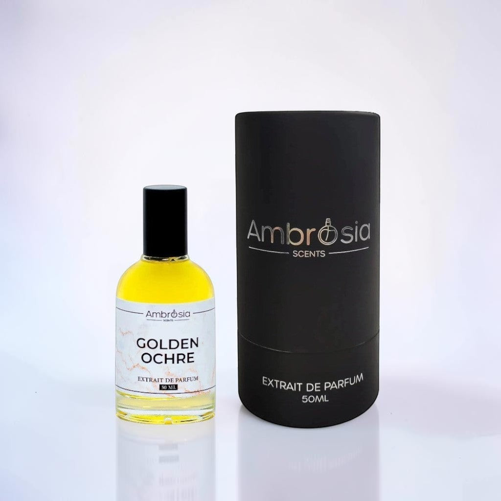 Ambrosia Scents Golden Ochre Extrait De Parfum, a golden yellow fragrance in a clear glass bottle with a black cap, next to its black cylindrical packaging.